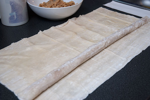 Step-by-step image guide: Spreading the luscious almond filling on a filo pastry sheet and rolling it for M'hanncha