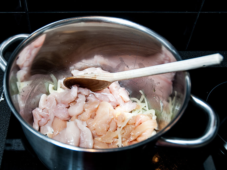 Raw chicken pieces and onions in a pot for making delicious chicken tagine recipe.