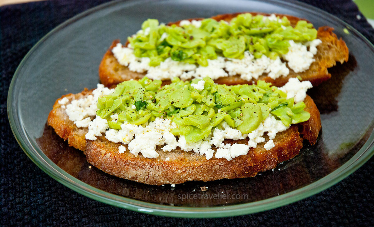 Savor the delicious combination of crushed boiled broad beans and crumbled tangy feta on rustic brown bread, a delightful treat that celebrates simple ingredients with bold flavours.