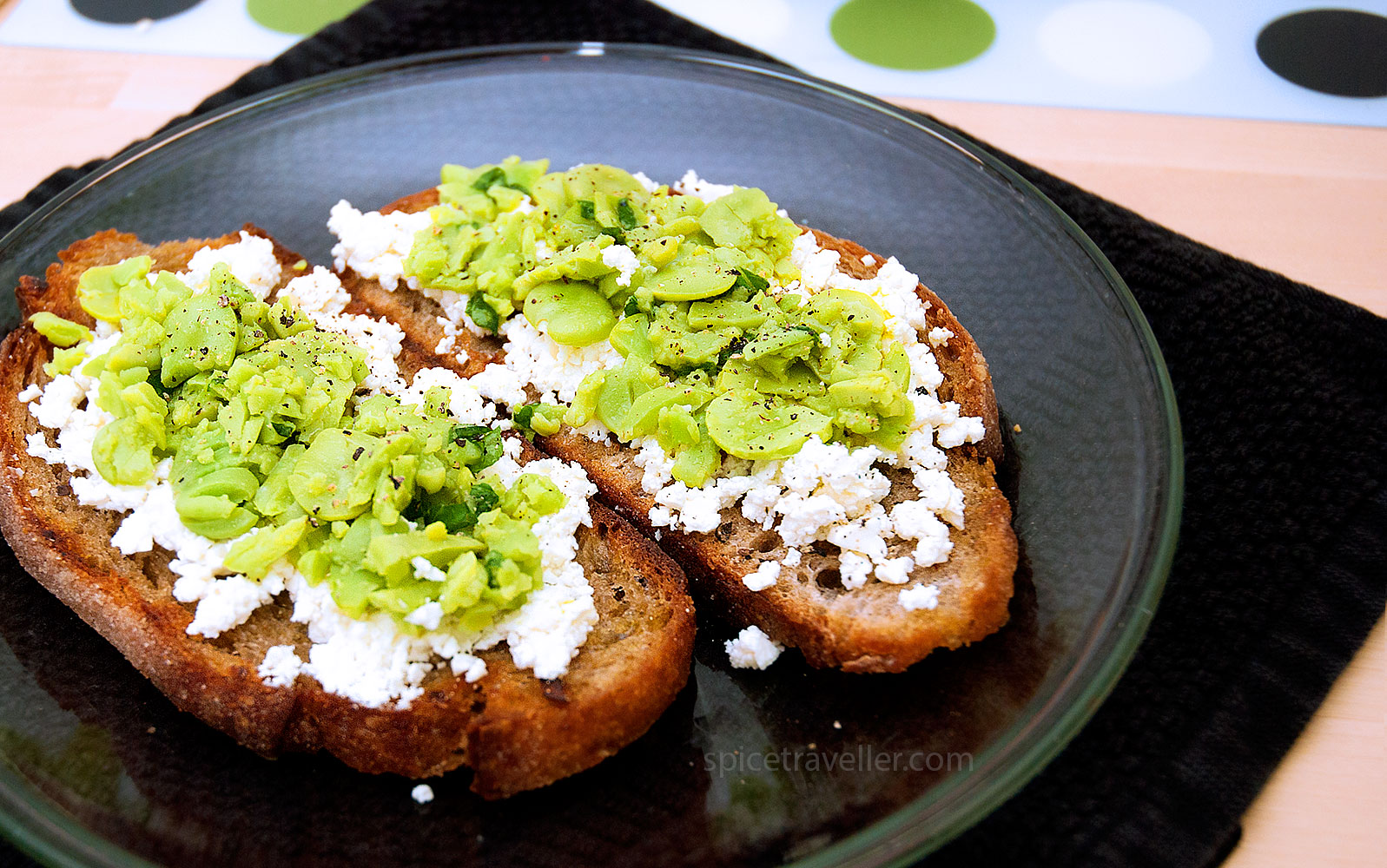 Savor the delicious combination of crushed boiled broad beans and crumbled tangy feta on rustic brown bread, a delightful treat that celebrates simple ingredients with bold flavours.