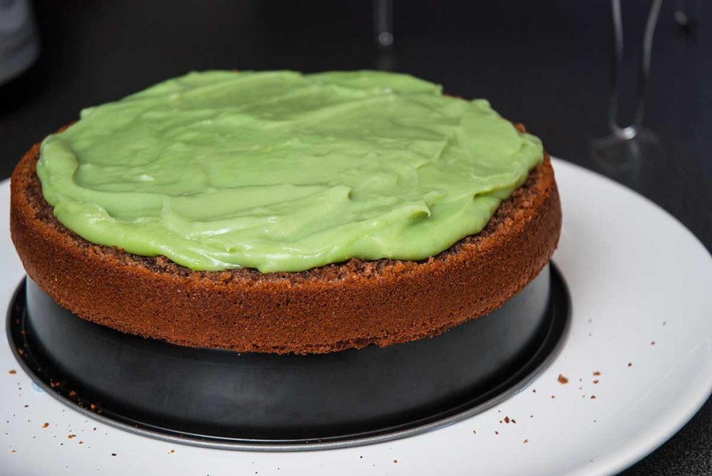 Spreading green cream over the first chocolate sponge cake layer. 