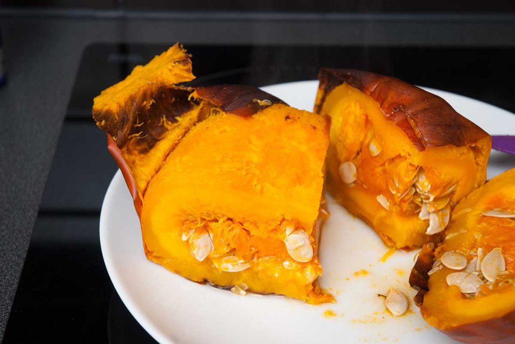 Removing skin and seeds from roasted pumpkin wedge.