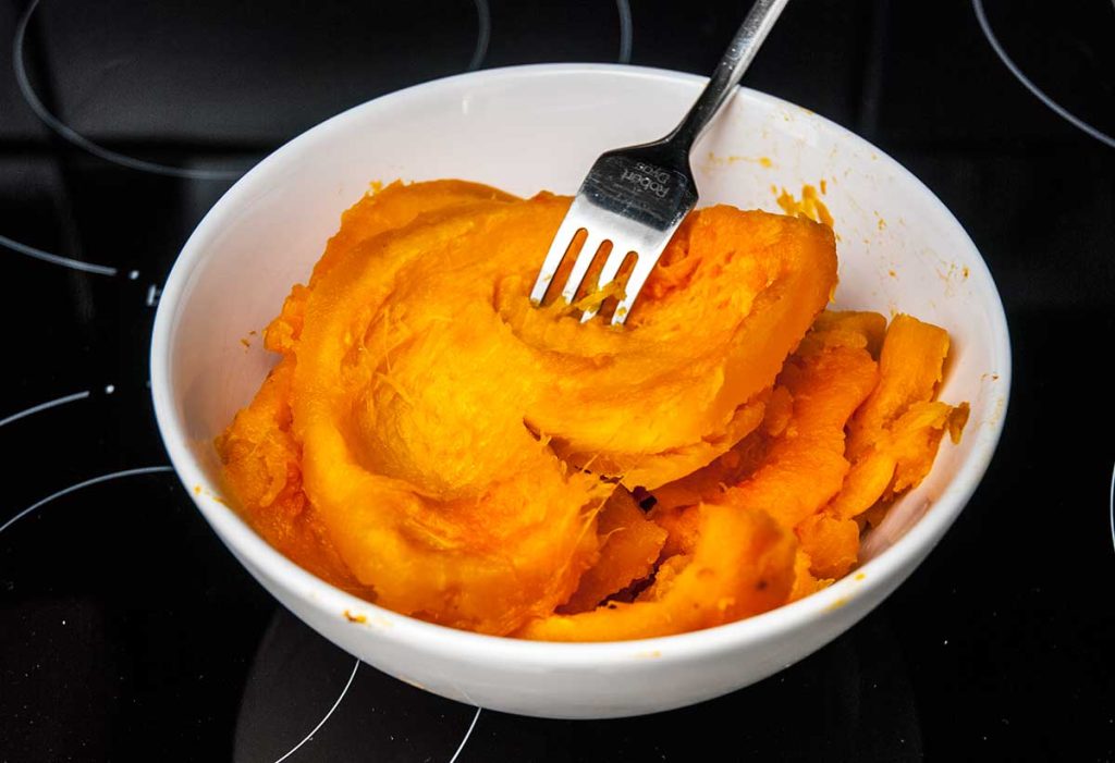 Bowl of scooped roasted pumpkin flesh.