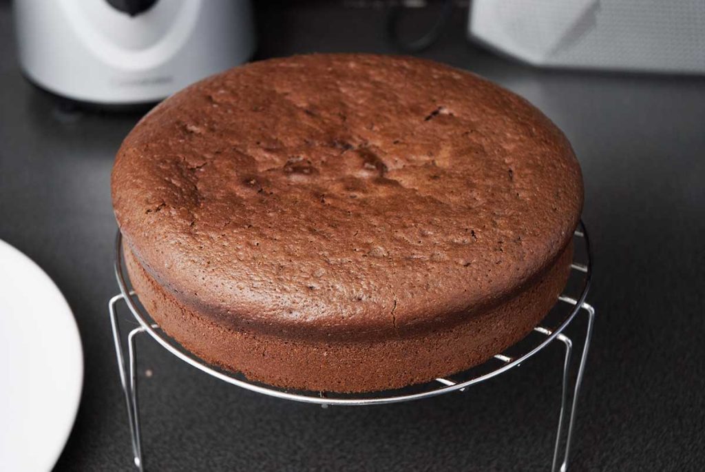 Cocoa and walnut sponge cake cooling on a rack.