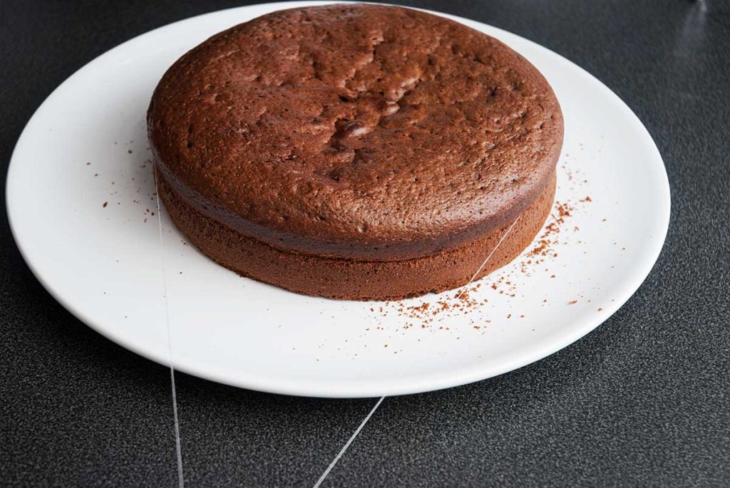 Using a piece of thread positioned around the walnut cake , slicing it into half in order to get two layers.