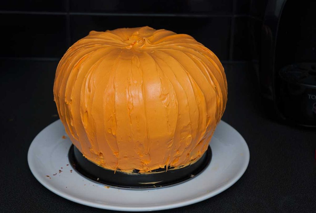 Completed: Halloween jack-o-lantern pumpkin and chocolate cake covered with final decorative orange icing. 