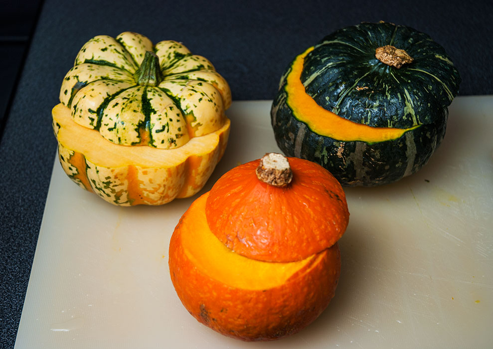 Step in preparing mini pumpkin bowls for risotto, showing the top of a mini pumpkin cut off to create a lid for the serving bowl.