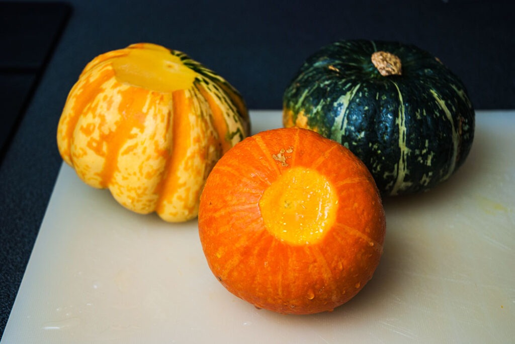 Step in preparing mini pumpkin bowls for risotto, featuring three mini pumpkins, one showing how to  cut bottom for stability.