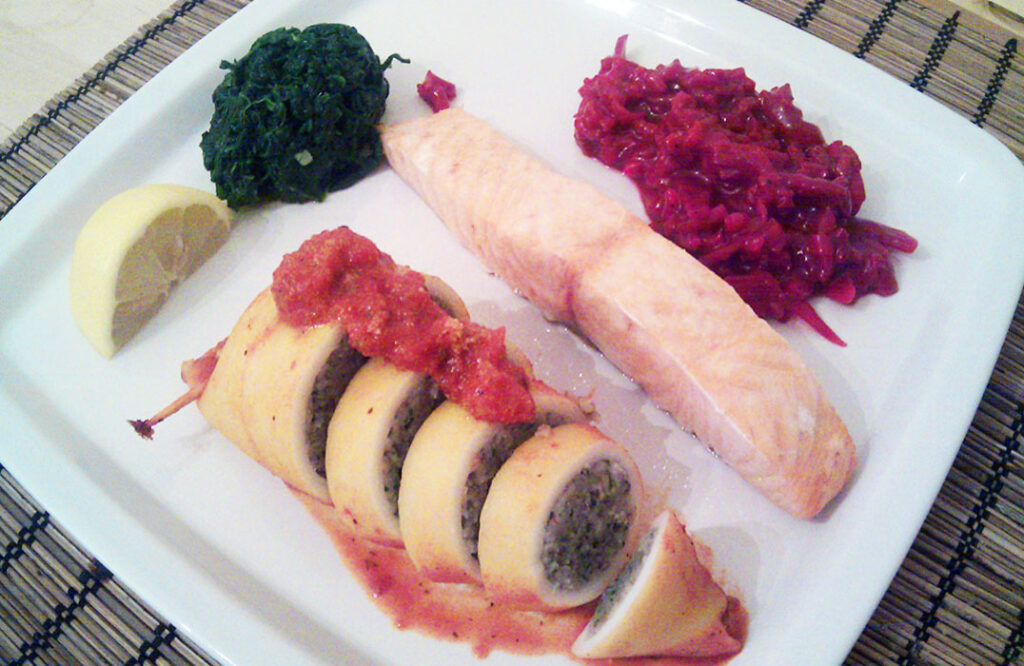 Mediterranean stuffed squid with tomato sauce topping served as a main meal alognside salmon and vegetables