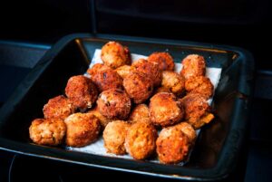 Perfectly fried golden chicken meatballs on a black plate resting