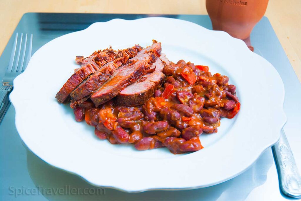 Baked beans served as a side dish together with four beef brisket slices