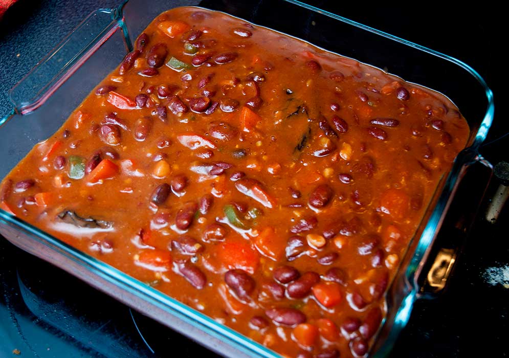 Spicy eans and vegetables placed in the baking dish and ready to bake