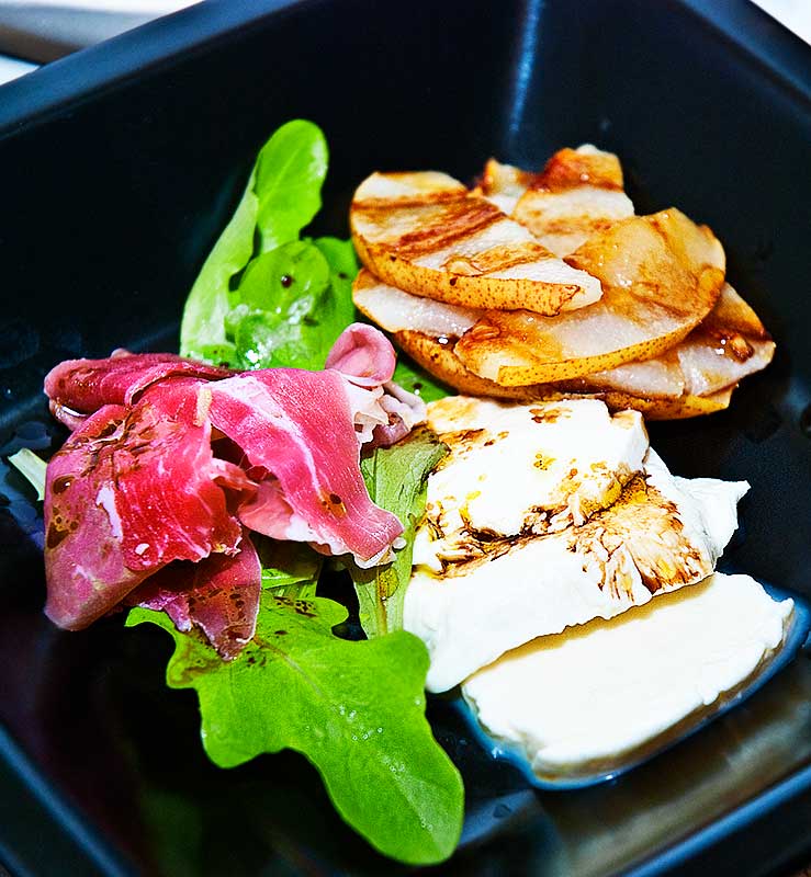 Italian salad with grilled pear slices, buffallo mozzarella cheese slices, wild rocket leaves and parma ham slice, drizzled with balsamic vinegar and olive oil
