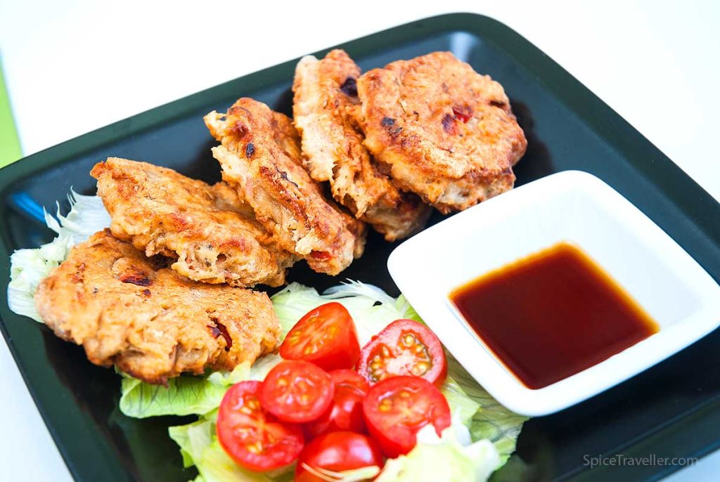 Korean fritters on black plate served with salad and dipping sauce.