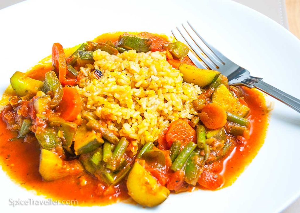 Bahraini vegetable stew served with rice on a white plate.