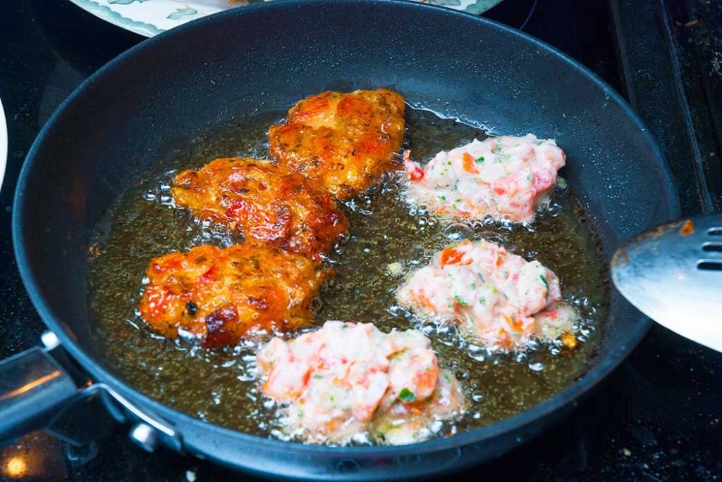 Greek tomato and feta fritters frying in a pan.