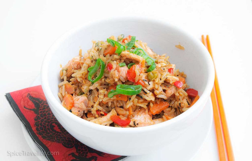 white bowl of delicious salmon fried rice, decorated with sliced green spring onion