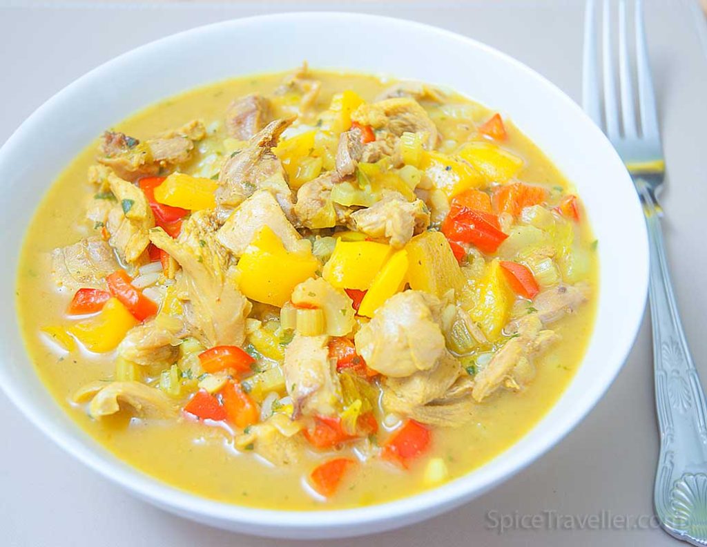 Serving suggestion: Bowl of delicious British-style creamy chicken curry, tender chicken pieces with red and yellow peppers.