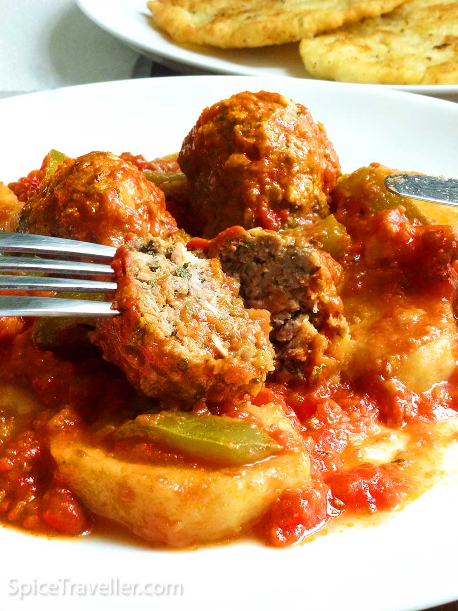 Close up of a delicious looking Turkish Kofta sliced in half covered with rich tomato sauce.