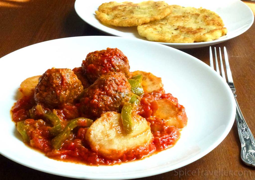 Turkish kofte meatballs with potato bake in tomato sauce served on a white plate