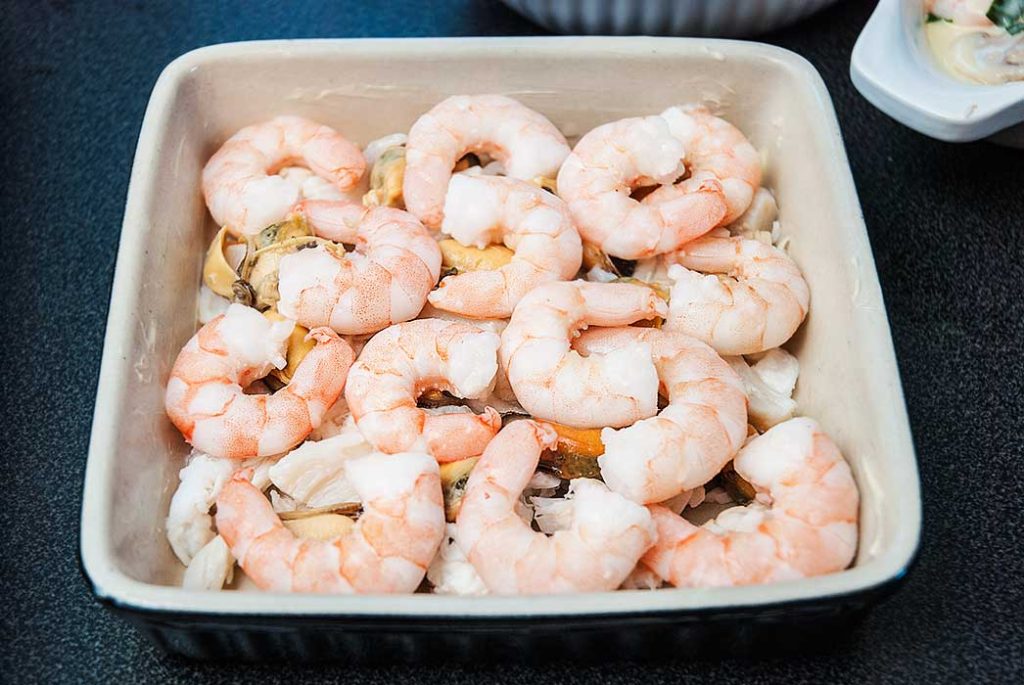 baking dish filled with fish and seafood, step one