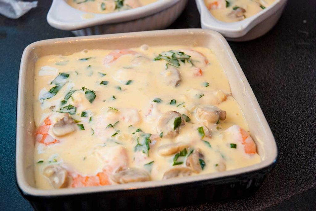 baking dish filled with fish, seafood and creamy sauce, step two