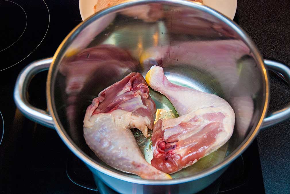 Chicken legs frying in a pot for POllo Guisado