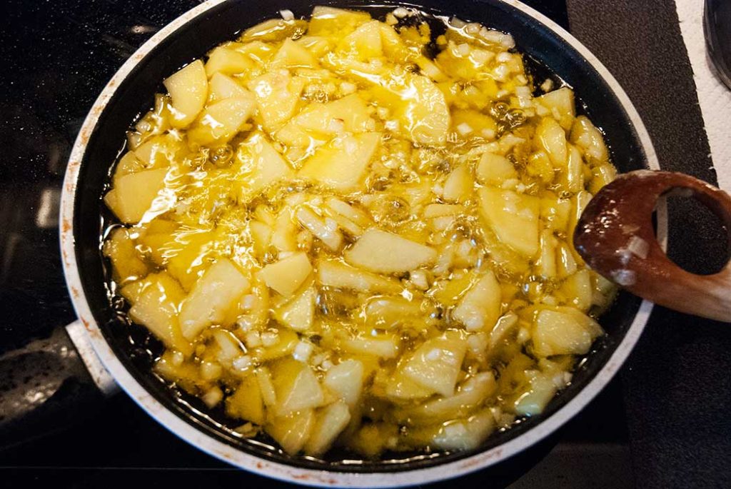 Potatoes and onions frying in lots of oil for Spansih Tortilla