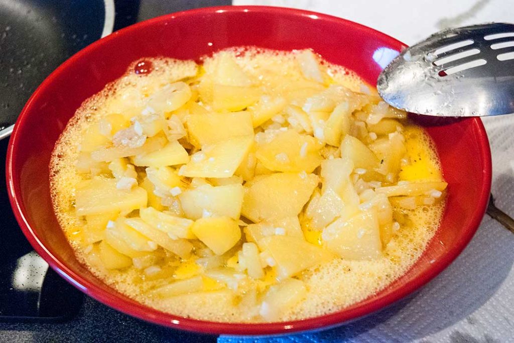 Fried potatoes and onions mixed with beaten egg, ready to make Spanish tortilla