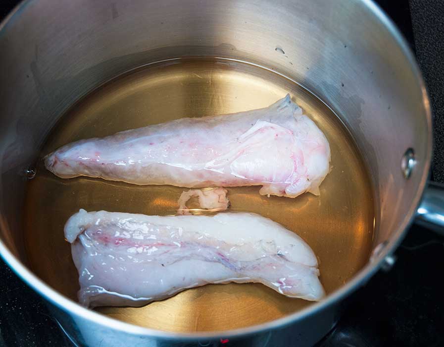 monkfish tail fillets in a pan with wine and water