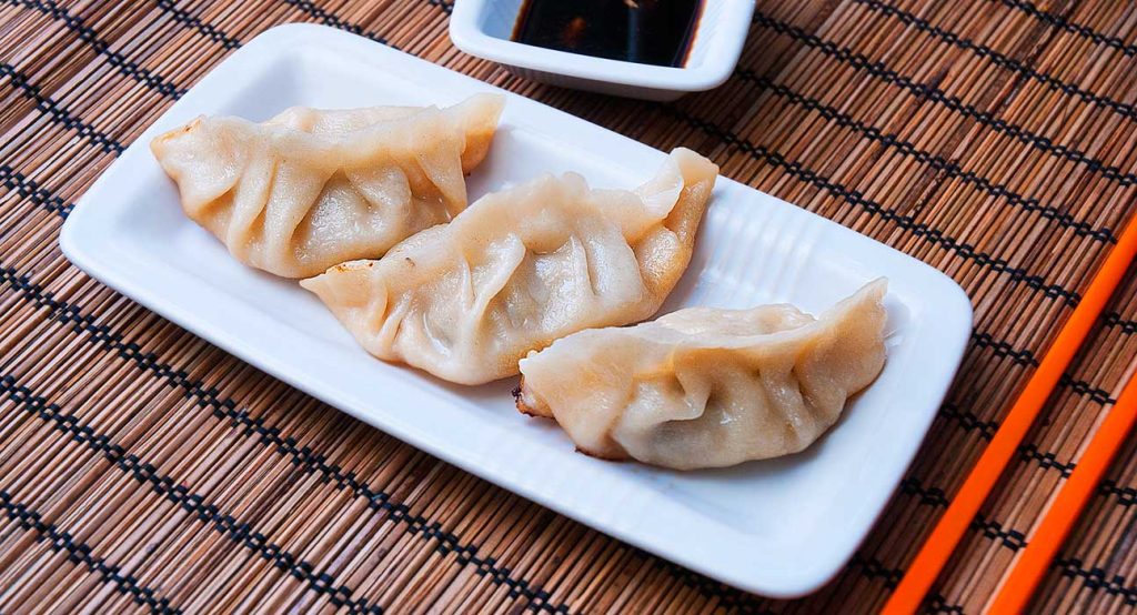 Three pieces of Chinese dumplings served with soy sauce dip.