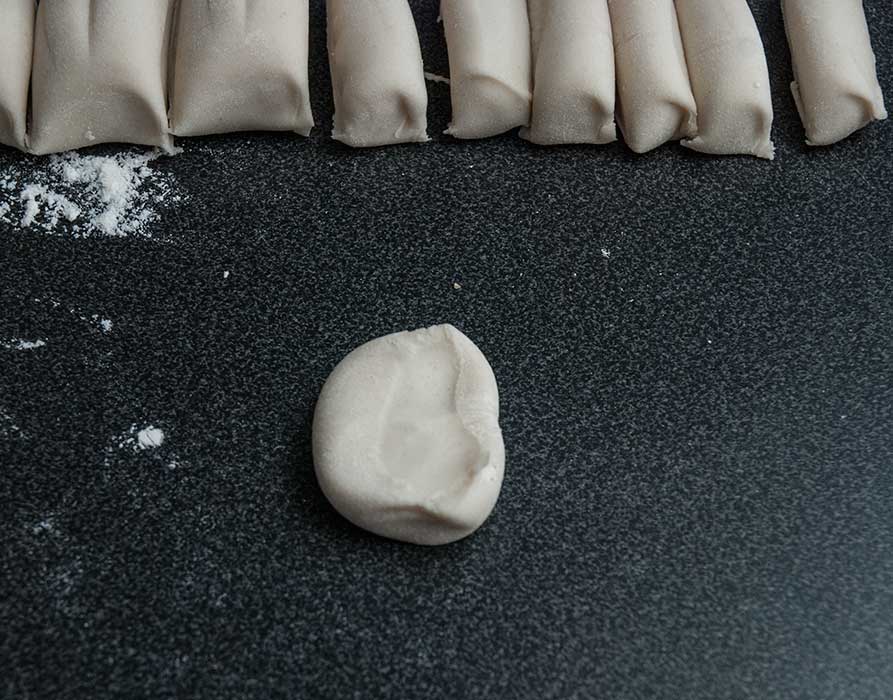 One piece of cut dough flattened with hand.