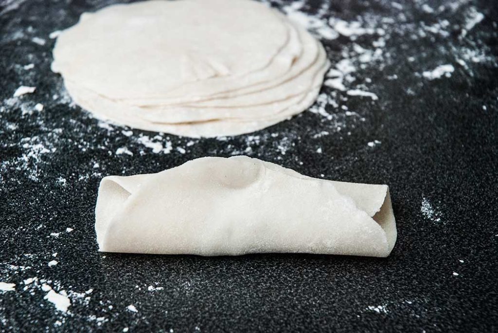 Rolled dough folded and pinched at the top.