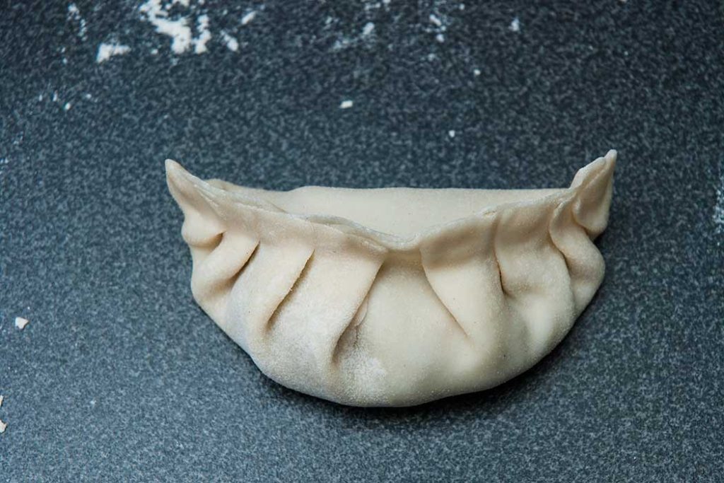 Close up of Chinese dumpling showing how it is pleated on the edge.