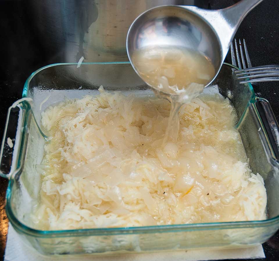 Adding chicken broth to the grated potatoes.