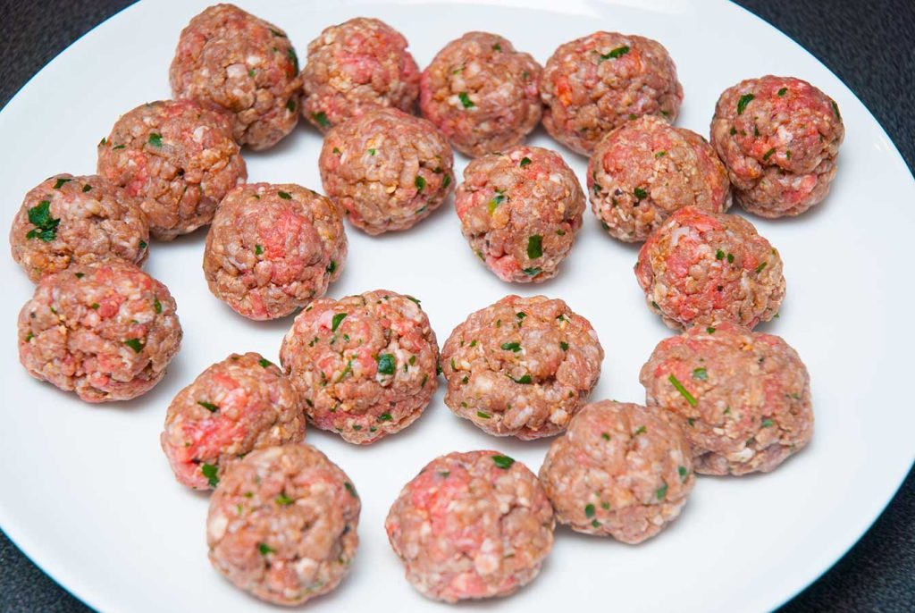 Perfectly shaped small beef meatballs resting before frying.