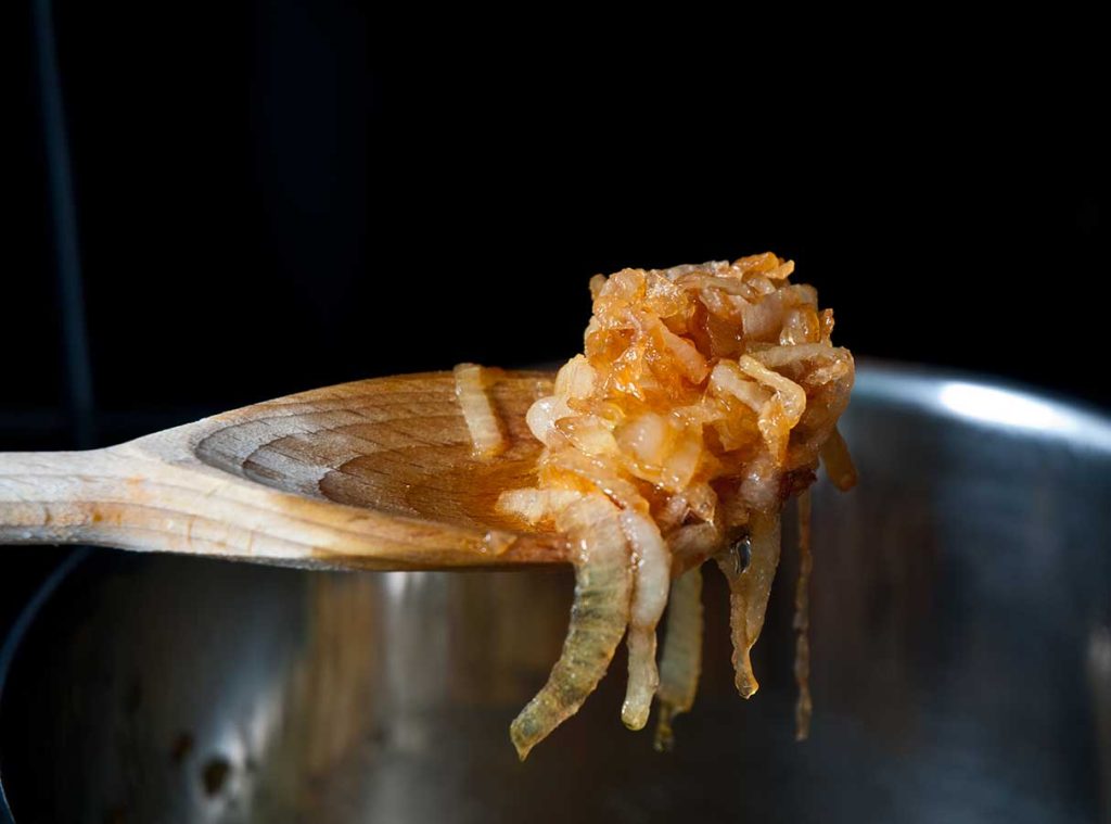 Close up of caramelised onion on a wooden spoon.