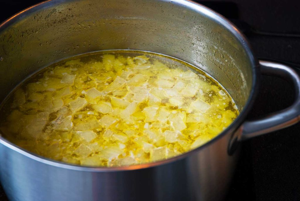 Chicken broth with onion pieces ready to use for Chicken and potato casserole - Rappie Pie.