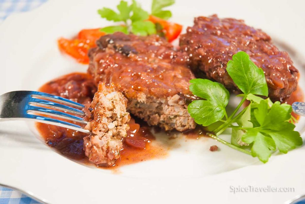 Closeup of Salisbury steak piece on a fork with delicious gravy.