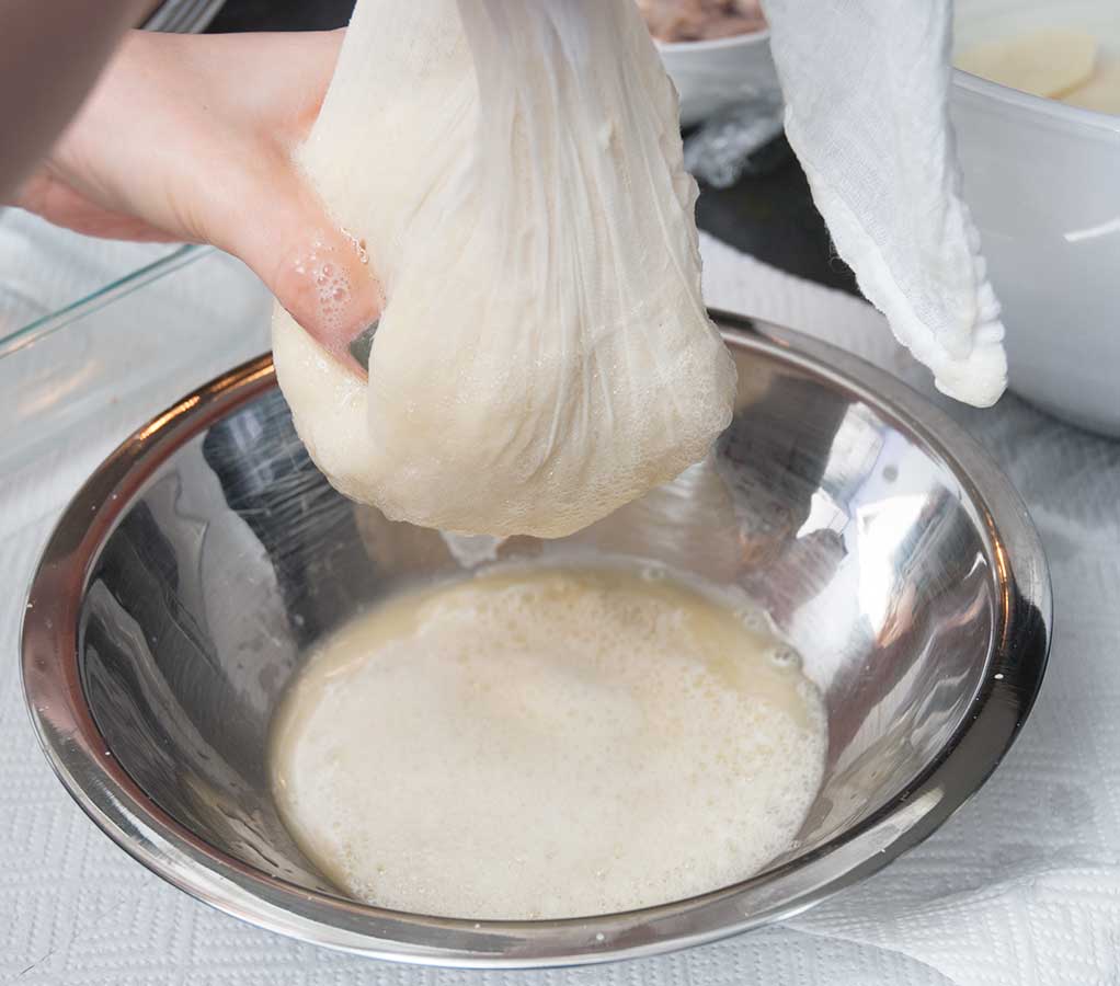 Squeezeing grated potatoes through a cheesecloth.