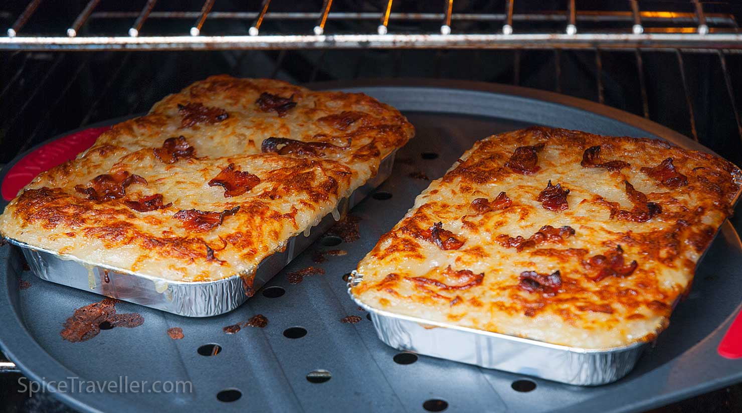 Two trays in the oven with perfectly baked chicken and potato casserole - Rappie Pie