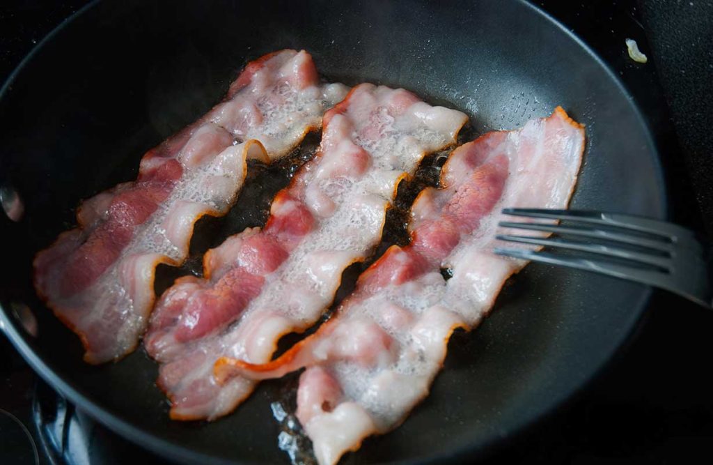 Frying bacon strips for Rappie pie.