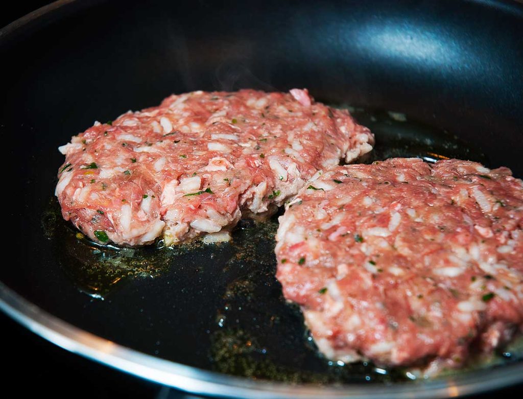 Minced beef burgers or patties frying. 