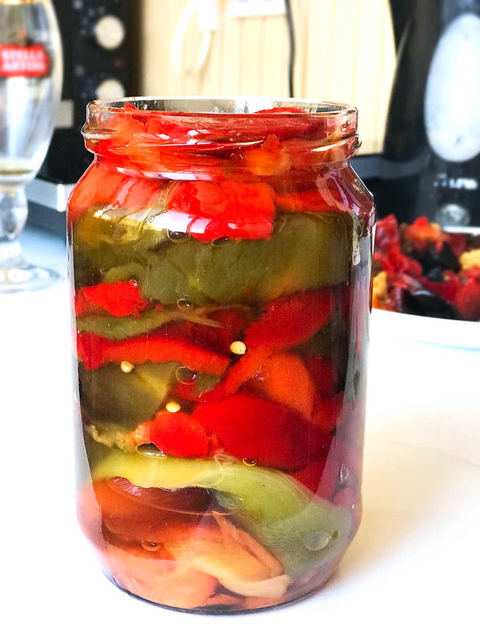 Close up of a large jar filled with roasted bell pepper fillets in natural juices.