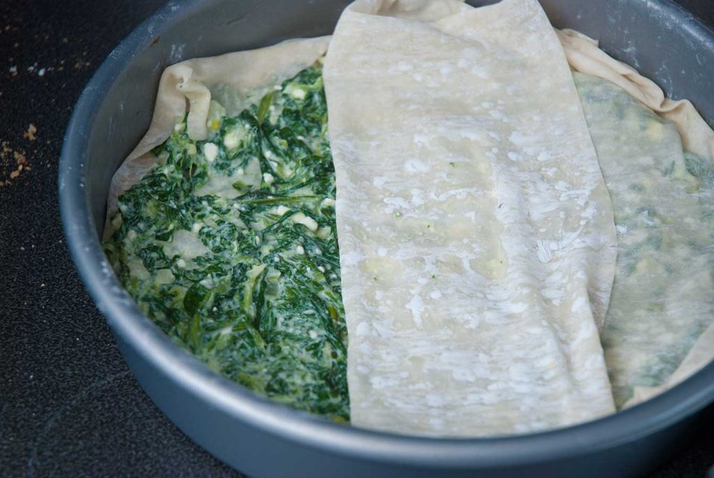 Assembling Albanian spinach and cheese borek pie.