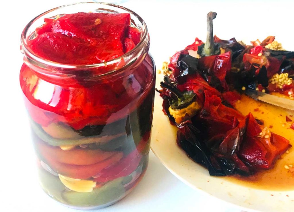 Jar filled with roasted bell peppers in different colours.