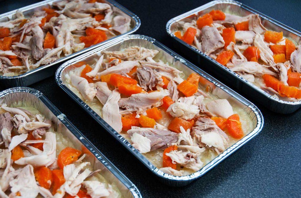 Layering chicken and carrots on grated potato.