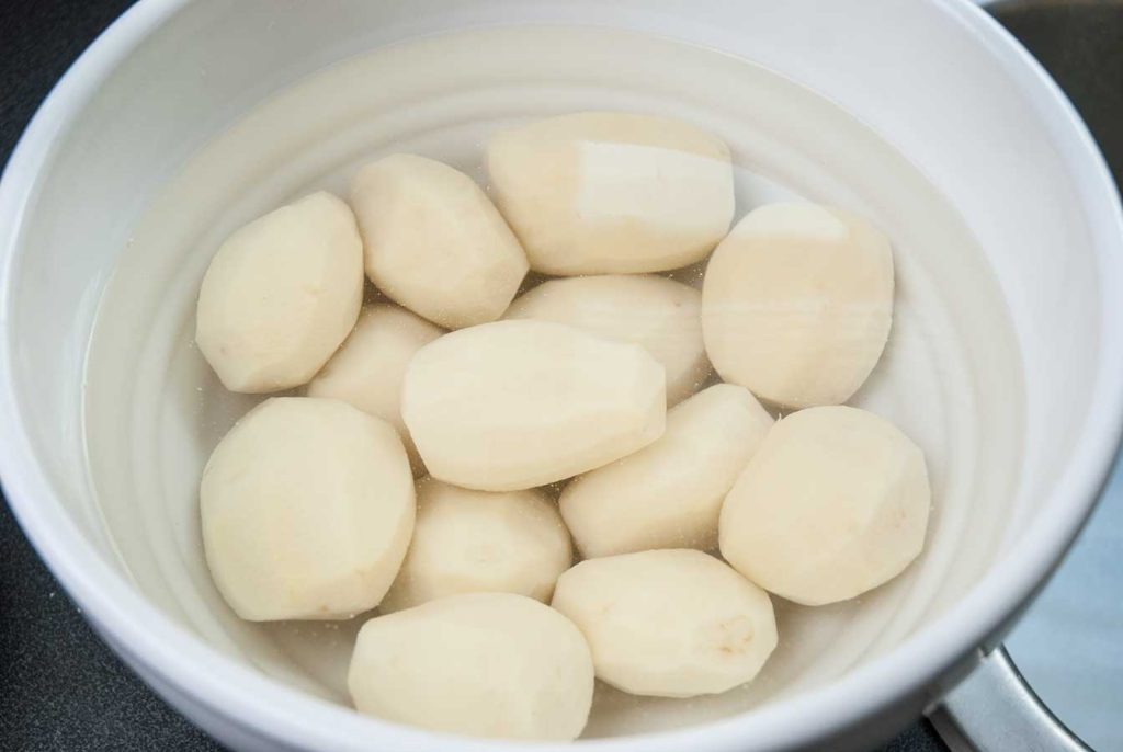 Peeled potatoes in a bowl of water.