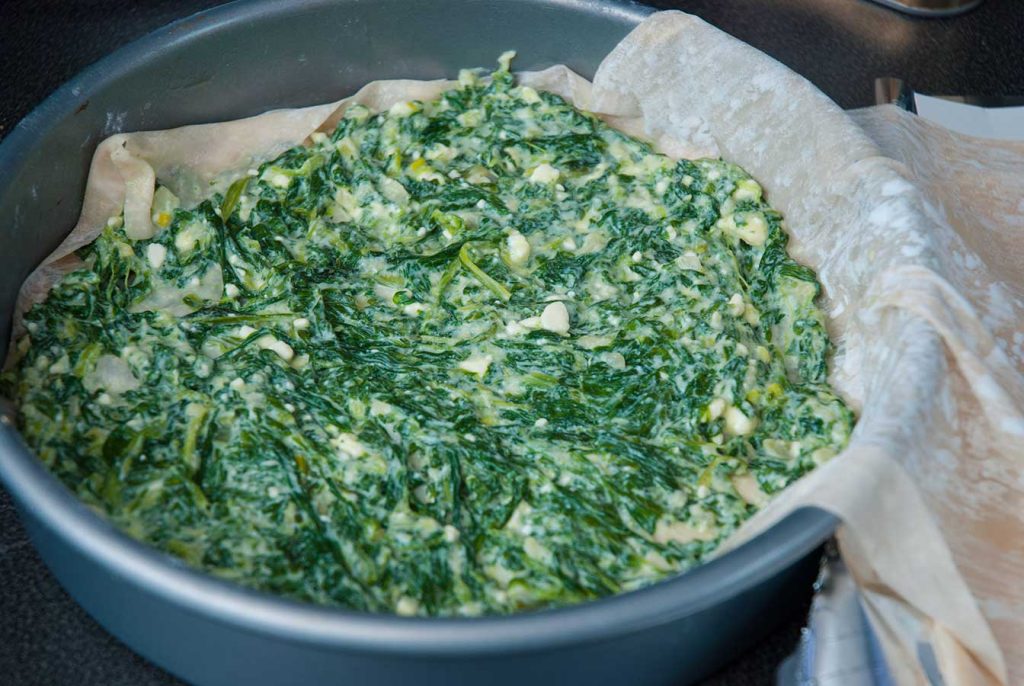 Spreading spinach mixture over filo dough.