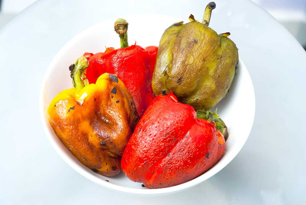 Four skinned bell peppers in a bowl before deseeding and fileting.